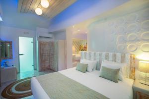 a bedroom with a large white bed and a bathroom at Rhodos Horizon Blu-Adults Only in Rhodes Town