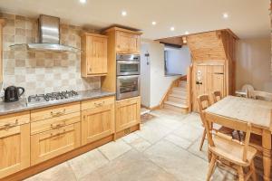 cocina con armarios de madera, mesa y comedor en Host & Stay - Jacksons Cottage, en Whitby
