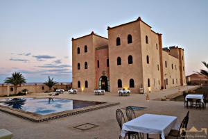 a large building with tables and chairs in front of it at Sunrise Palace Merzouga in Merzouga