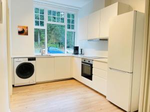 Il comprend une cuisine blanche équipée d'un réfrigérateur et d'un lave-vaisselle. dans l'établissement aday - Aalborg mansion - Big apartment with garden, à Aalborg