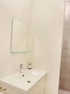 La salle de bains blanche est pourvue d'un lavabo et d'un miroir. dans l'établissement aday - Aalborg mansion - Big apartment with garden, à Aalborg