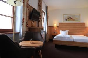 a hotel room with a bed and a table and chairs at Neckarblick SELF Check IN Hotel in Bad Wimpfen