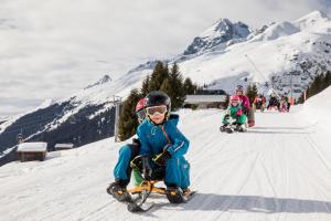 a young child riding a snow bike in the snow at Pradas Resort Brigels in Brigels