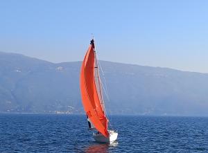 een zeilboot met een oranje zeil in het water bij Hotel Garnì Bartabel in Gargnano