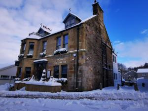 un grande edificio in mattoni con neve di fronte di The Balerno Inn a Edimburgo