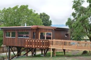 une grande maison en bois sur une terrasse en bois dans l'établissement Cabane dans les arbres / Swin-golf de Cremin, à Cremin