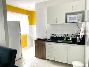 uma cozinha com armários brancos e um micro-ondas em Hotel APART Zuccolotto 301 em Aracruz