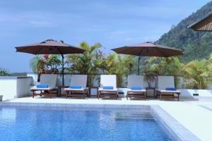 a swimming pool with chairs and umbrellas next to a pool at Kulraya Villas - Luxury Serviced Pool Villas in Ko Lanta