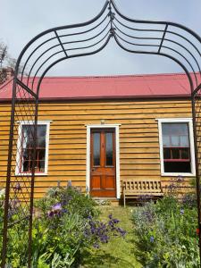 uma casa amarela com um telhado vermelho e um banco em Portobello Settler's Cottage em Portobello