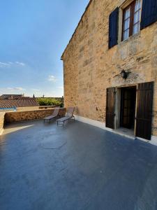 a pair of benches sitting on a patio next to a building at Suite parentale Castillon du Gard in Castillon-du-Gard