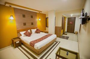 una camera con un letto in una stanza con pareti gialle di Hotel Maneck Residency a Ooty