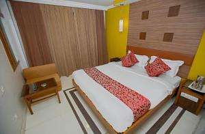a bedroom with a large bed with red pillows at Hotel Maneck Residency in Ooty