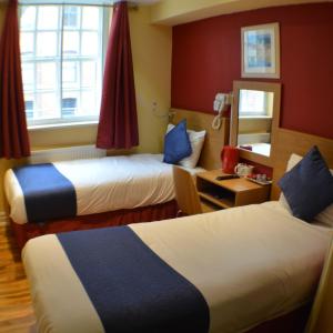 a bedroom with two beds and two windows at Ville Hotel in Manchester