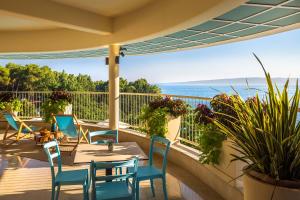eine Terrasse mit einem Tisch, Stühlen und Meerblick in der Unterkunft Koralj Sunny Hotel by Valamar in Krk