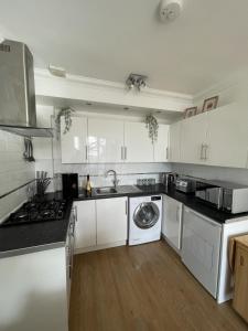 a kitchen with white cabinets and a washing machine at Modern 2 bed apartment with sea views in Torquay