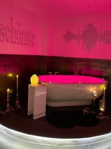 een roze badkamer met een bad met een tafel en kaarsen bij Bernrieder Hof in Bernried