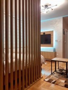 um quarto com uma divisória em madeira com uma cama e uma mesa em Apartman Planinski Kutak em Pale