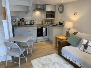 a living room with a couch and a table and a kitchen at The Nook at Pentregaer Ucha, with tennis court & lake. in Oswestry