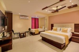 a hotel room with two beds and a desk at Hotel Malad Inn opposite Malad Railway Station in Mumbai