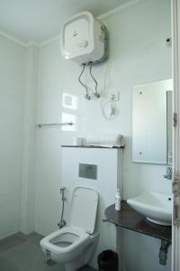 a white bathroom with a toilet and a sink at Lime Tree Luxurious 3BHK Serviced Apartment Near Medanta in Gurgaon +83 photos