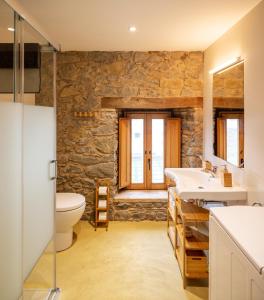 a bathroom with a stone wall and a toilet and sink at El Rebastral - Mas Vinyoles Natura in Sant Pere de Torelló