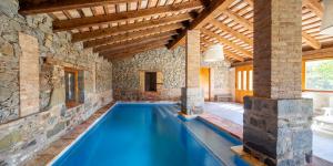 an indoor pool in a house with a stone wall at El Rebastral - Mas Vinyoles Natura in Sant Pere de Torelló