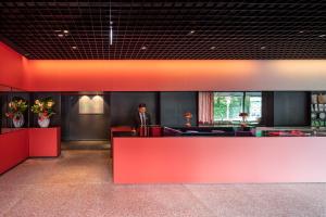 a man standing behind a red counter in a lobby at Casa Camper Berlin in Berlin