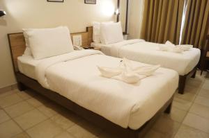 um quarto de hotel com duas camas com lençóis brancos em Sharayu One em Mapuçá
