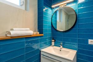 a blue tiled bathroom with a sink and a mirror at SarmiHouse in Cluj-Napoca +49 photos