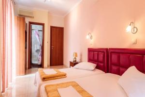 a bedroom with two beds and a red headboard at Christina Hotel in Olympic Beach