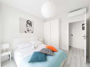 biała sypialnia z łóżkiem z poduszkami w obiekcie Capital Apartments - Towarowa w Poznaniu