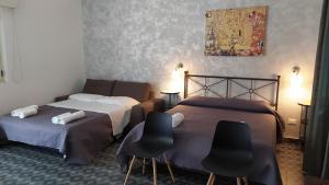 トリーノ・ディ・サングロにあるRelais Il Giardino fra gli Uliviのベッド2台、椅子2脚、絵画が備わる客室です。