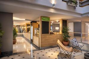 eine Lobby eines Hotels mit Stühlen und Pflanzen in der Unterkunft Koralj Sunny Hotel by Valamar in Krk
