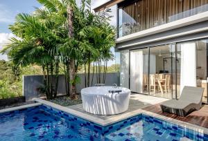 una bañera junto a una piscina junto a una casa en Gioheven Villa, en Nusa Dua