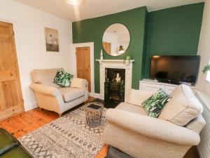 a living room with two chairs and a flat screen tv at Court Cottage in Ripon