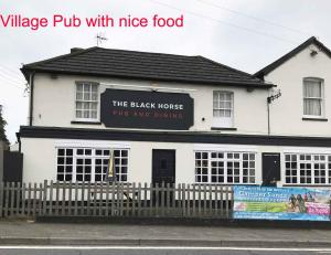 a white building with a black horse pub and dining at Bean Farm House Apartment in Stonewood