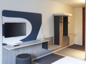 um quarto com uma televisão na parede em ibis Styles Beauvais em Beauvais