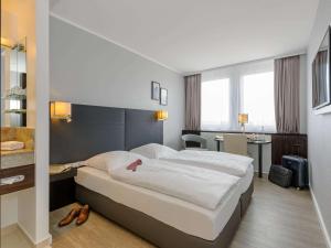 ein Hotelzimmer mit einem großen Bett und einem Bad in der Unterkunft Mercure Hotel Potsdam City in Potsdam