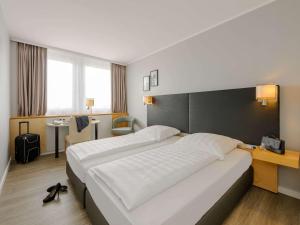ein Hotelzimmer mit einem großen Bett und einem Schreibtisch in der Unterkunft Mercure Hotel Potsdam City in Potsdam