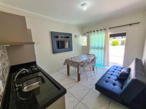 a kitchen and living room with a couch and a table at Miragem de Bombinhas DUO in Bombinhas