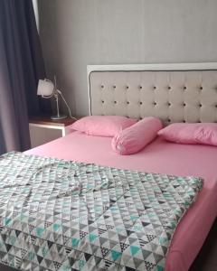 a bed with pink pillows and a pink comforter at Altiz Apartment Bintaro Plaza Residence in Tangerang