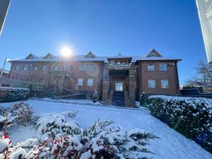 a building with snow on the ground in front of it at Resident Hotel Kaskelen in Kaskelen