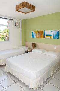 two beds in a room with green walls at Gran Lençóis Flat Residence 2 suítes com sala in Barreirinhas