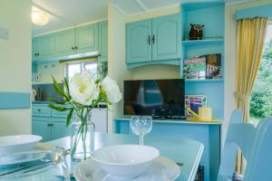 uma cozinha com armários azuis e um vaso de flores sobre uma mesa em Wind In The Willows: Sleeps 4, Kitchen, bathroom, lounge, WIFI em Napton on the Hill