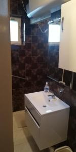 ザマールディにあるFecske Home Zamárdiの- 白いシンクと茶色のタイルを用いたバスルーム