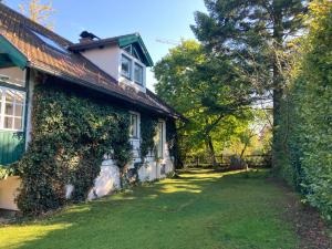 una casa cubierta de hiedra con un patio al lado en Haus mit Sauna und privatem Badeteich in Anif bei Salzburg en Anif