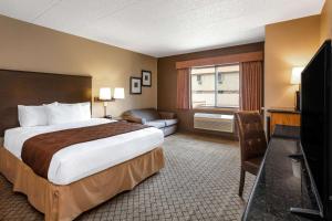 a hotel room with a bed and a flat screen tv at AmericInn by Wyndham Hartford WI in Hartford