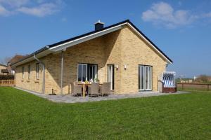 una casa de ladrillo con mesa y sillas en un campo en Ferienhaus Kuestenhaus, en Pommerby