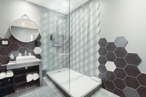 a bathroom with a shower and a sink and a mirror at The Originals Boutique, Hôtel Le Lion, Clermont-Ferrand in Clermont-Ferrand +56 photos