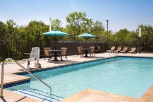 una piscina con mesas, sillas y sombrillas en La Quinta Inn & Suites by Wyndham San Antonio Seaworld LAFB, en San Antonio